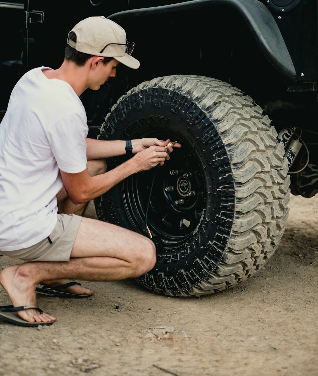 Technician kneeling beside a vehicle, working on its wheel