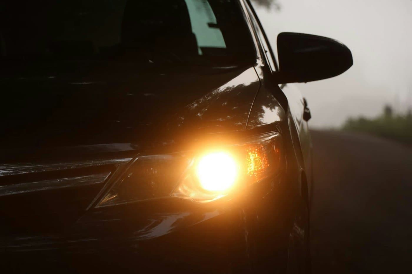 Car headlight glowing on a dark roadside