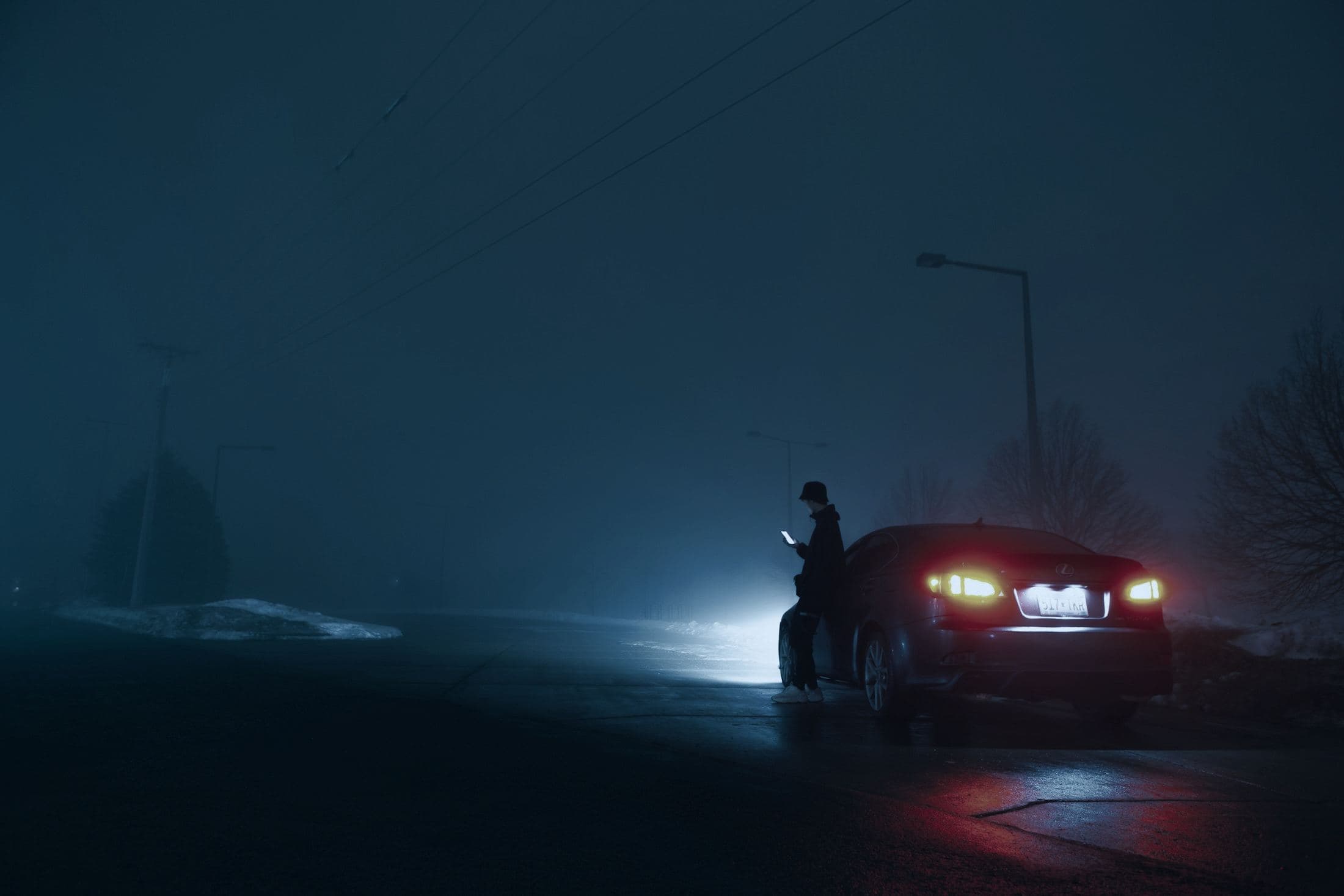 Driver on the phone beside a car stopped at the roadside at night