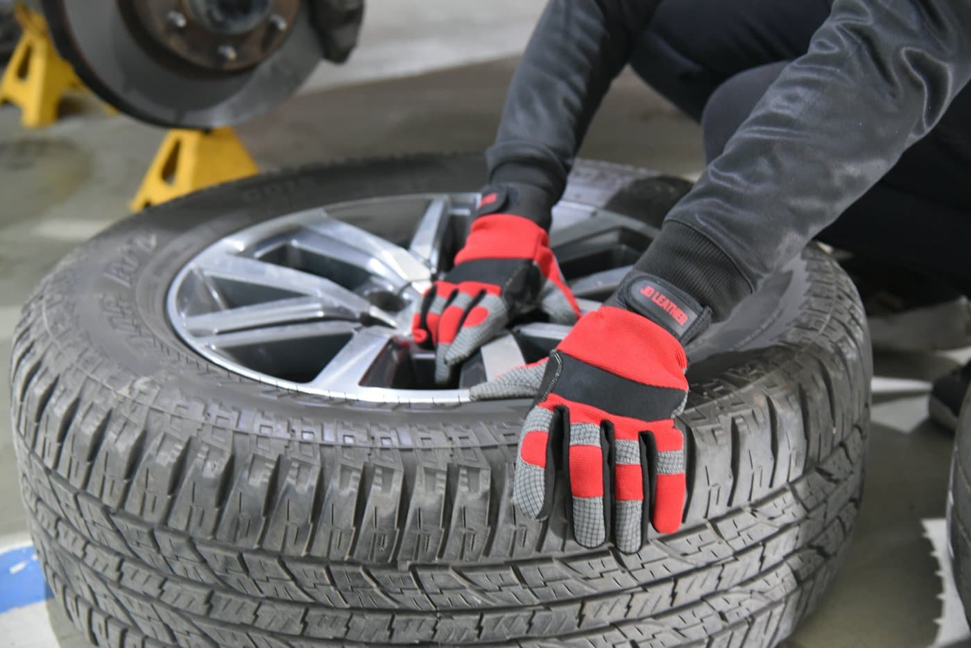 Gloved hands fitting a tire onto an alloy wheel